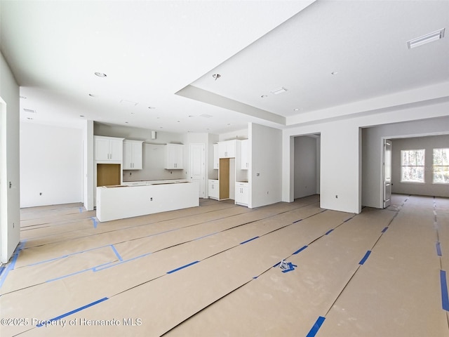 unfurnished living room with visible vents and a raised ceiling