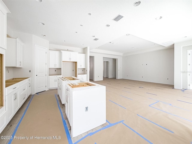 kitchen featuring a center island, white cabinets, and visible vents