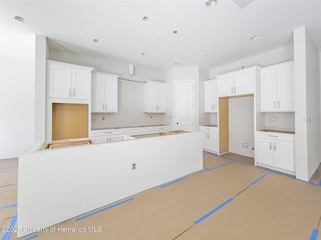 kitchen featuring concrete flooring, a kitchen island, and white cabinets