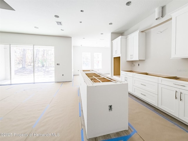 kitchen with a kitchen island, visible vents, white cabinets, and recessed lighting