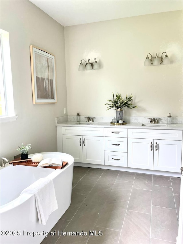 bathroom featuring a sink, a soaking tub, and tile patterned flooring