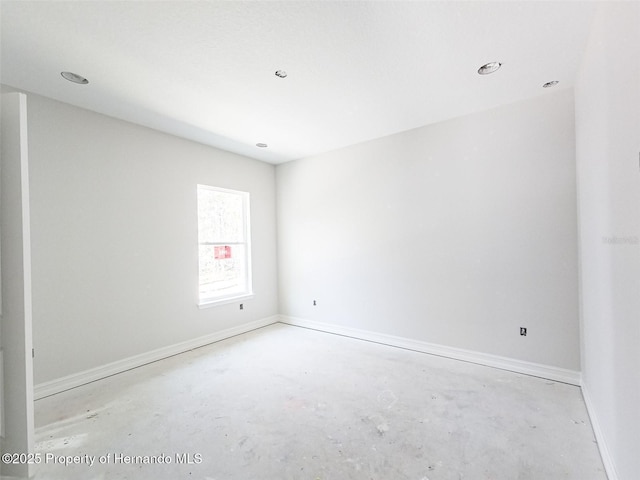 spare room with unfinished concrete flooring and baseboards