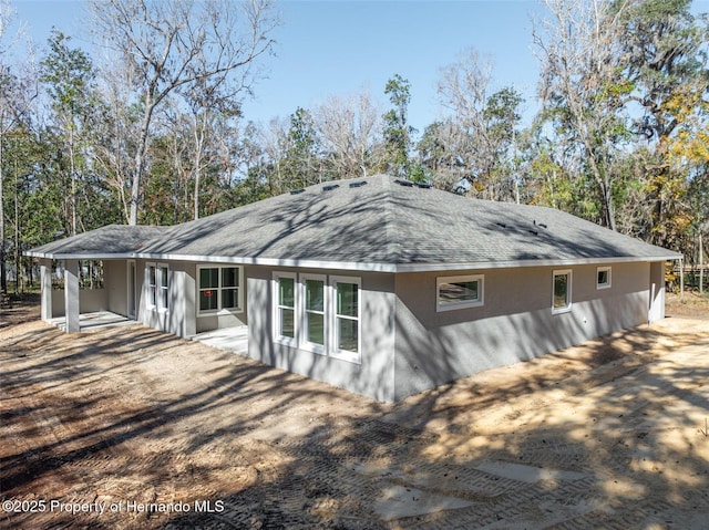 view of side of home featuring a shingled roof and stucco siding