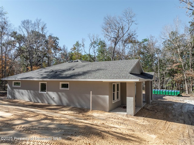 view of property exterior with roof with shingles and stucco siding