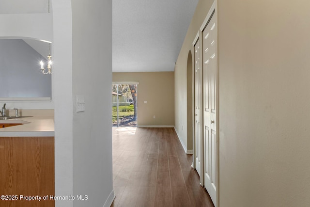 corridor with a sink, baseboards, and wood finished floors