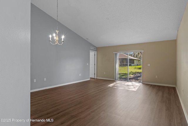 unfurnished room featuring a textured ceiling, wood finished floors, baseboards, vaulted ceiling, and an inviting chandelier