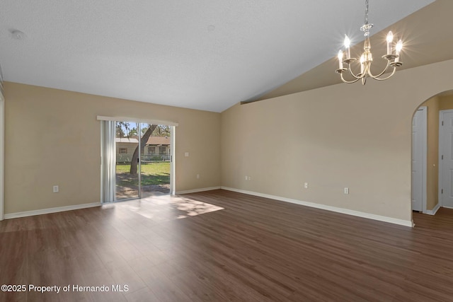 spare room featuring lofted ceiling, an inviting chandelier, arched walkways, and dark wood-style flooring