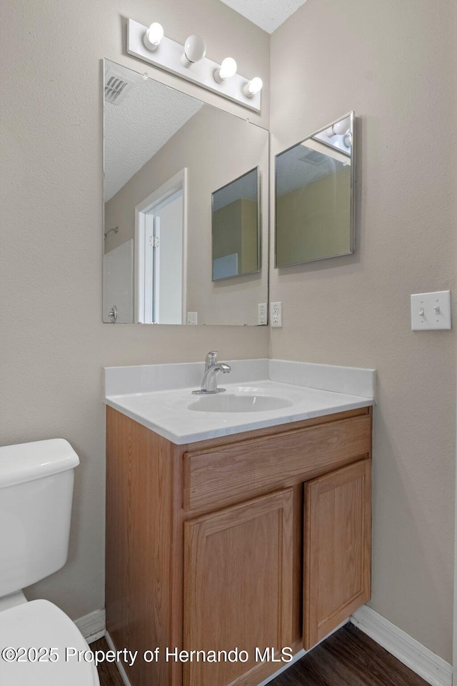 bathroom featuring toilet, wood finished floors, vanity, and baseboards