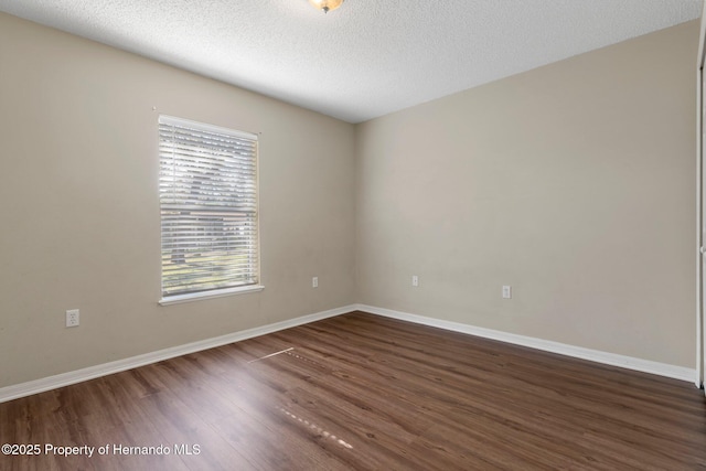 spare room with dark wood finished floors, a textured ceiling, and baseboards