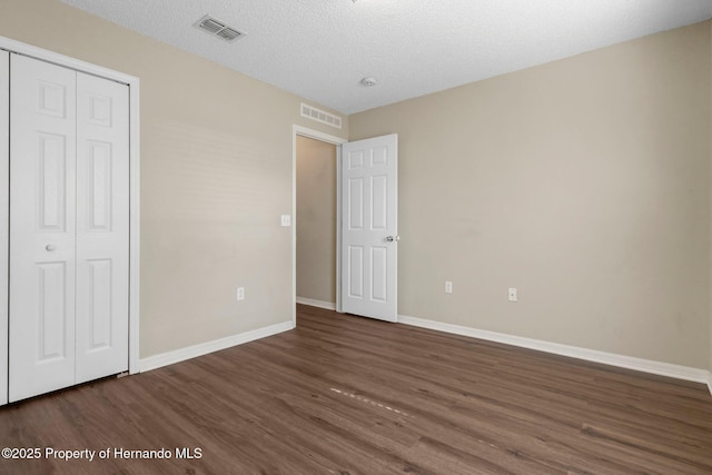 unfurnished bedroom featuring visible vents, baseboards, and wood finished floors