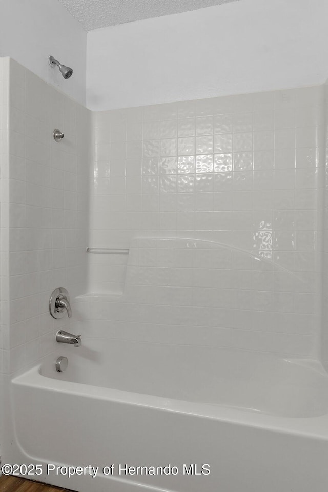 bathroom featuring bathing tub / shower combination and a textured ceiling