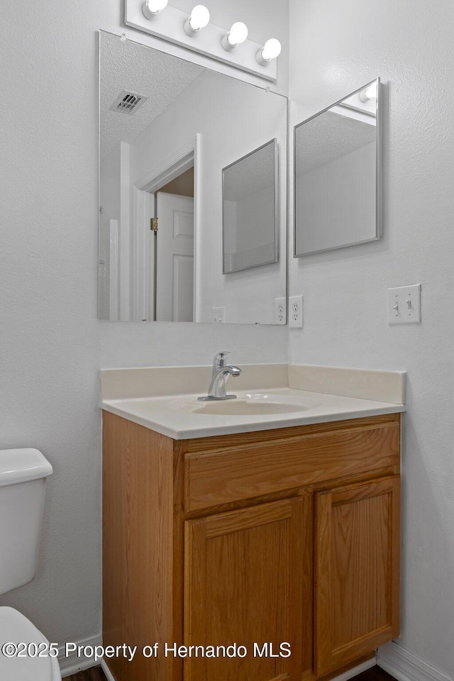 bathroom featuring toilet, visible vents, and vanity