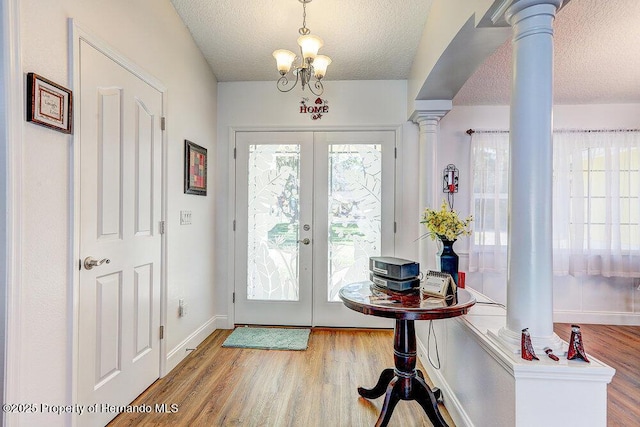 doorway to outside featuring french doors, a textured ceiling, ornate columns, and wood finished floors