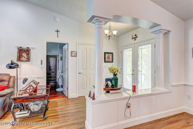 interior space featuring decorative columns, light wood-style flooring, and a textured ceiling