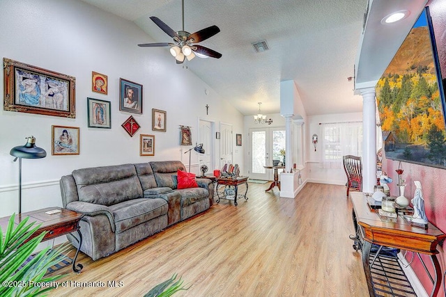 living area featuring visible vents, ceiling fan, a textured ceiling, wood finished floors, and ornate columns