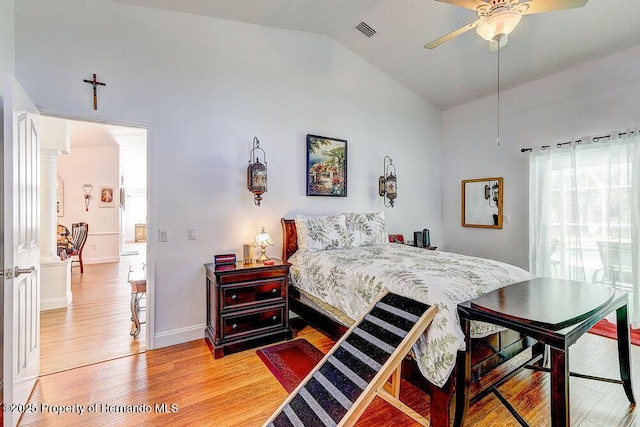 bedroom with light wood finished floors, lofted ceiling, ornate columns, visible vents, and baseboards