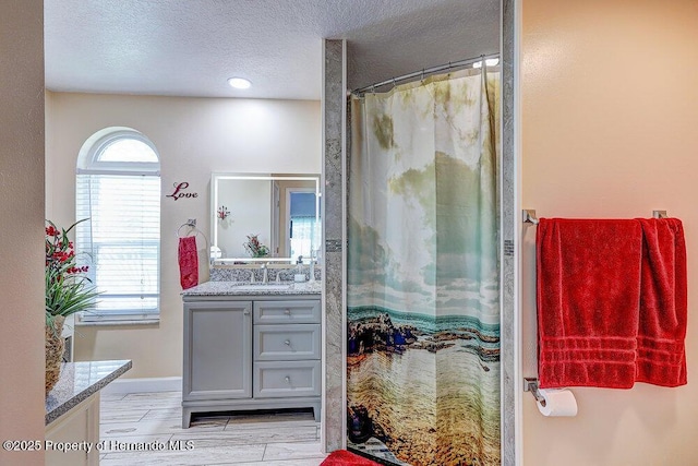 bathroom featuring a shower with shower curtain, baseboards, a textured ceiling, and vanity