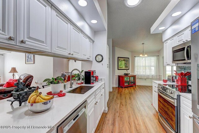 kitchen featuring appliances with stainless steel finishes, white cabinets, a sink, and light countertops