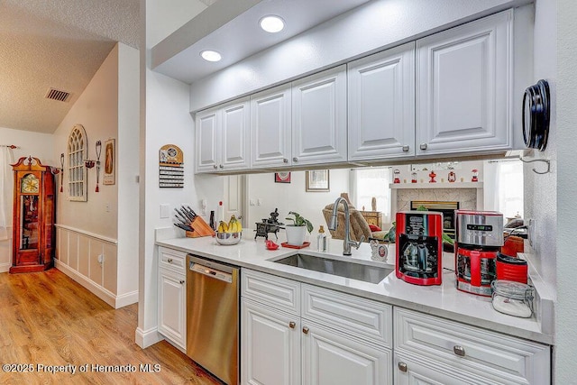 kitchen featuring a sink, visible vents, white cabinets, light countertops, and dishwasher