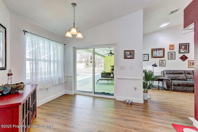 dining space with visible vents, an inviting chandelier, vaulted ceiling, a textured ceiling, and wood finished floors