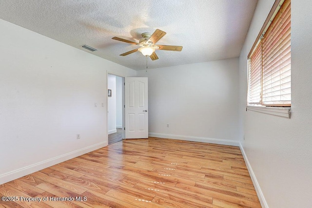 empty room with visible vents, baseboards, a ceiling fan, light wood-style flooring, and a textured ceiling