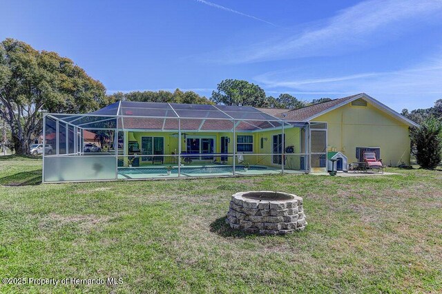 back of house with a lanai, a fire pit, a yard, a swimming pool, and a patio area