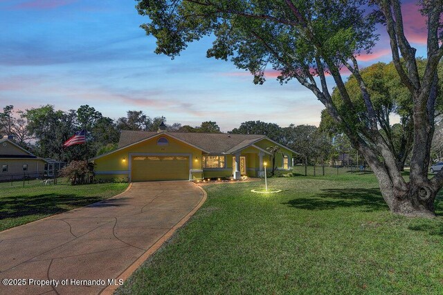 view of front of house with a garage, a yard, fence, and driveway