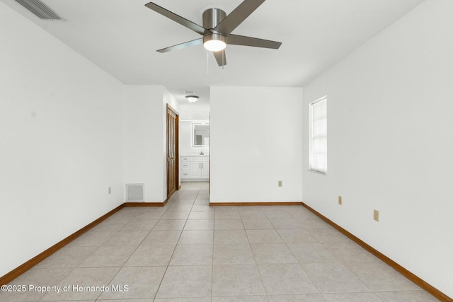 empty room with light tile patterned floors, visible vents, and baseboards