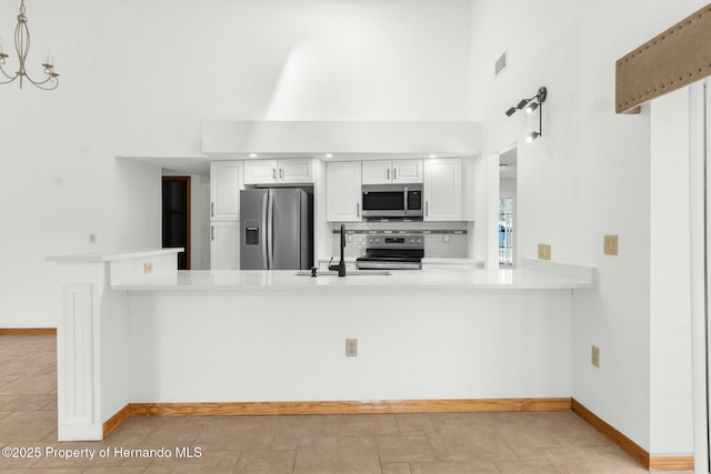 kitchen featuring a peninsula, stainless steel appliances, a sink, and light countertops
