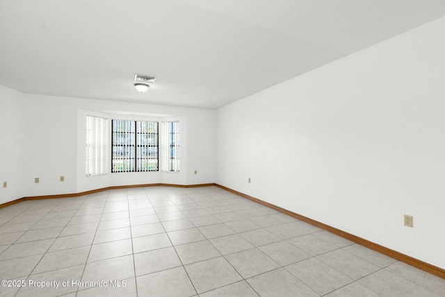 unfurnished room featuring light tile patterned floors, visible vents, and baseboards