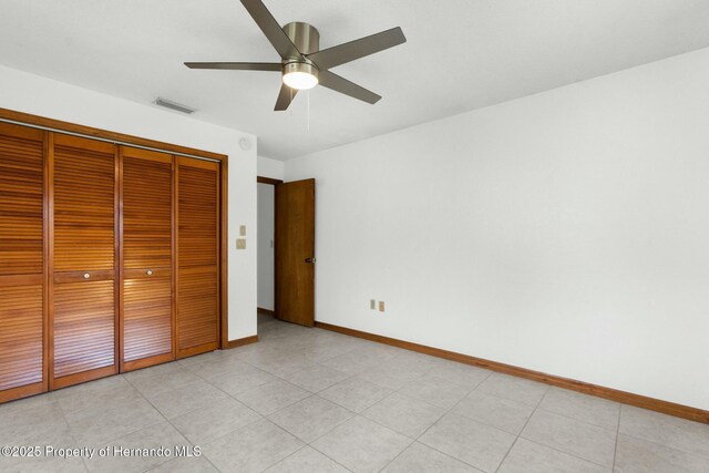 unfurnished bedroom with ceiling fan, light tile patterned floors, visible vents, baseboards, and a closet