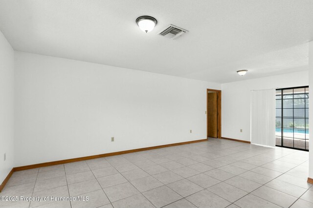 empty room with visible vents, baseboards, and light tile patterned floors