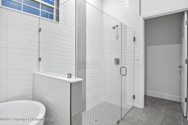 bathroom with a soaking tub, a stall shower, and baseboards