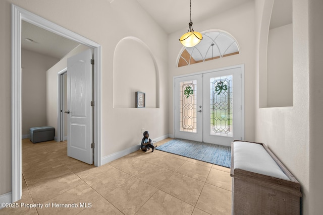 entrance foyer with high vaulted ceiling, french doors, tile patterned flooring, and baseboards