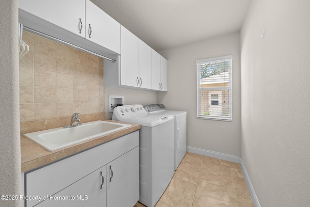 laundry room featuring light tile patterned floors, washing machine and dryer, a sink, baseboards, and cabinet space