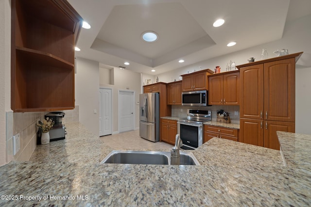 kitchen featuring a sink, stainless steel appliances, a tray ceiling, and open shelves