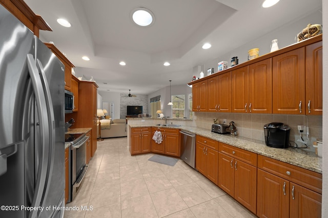 kitchen with recessed lighting, a sink, open floor plan, appliances with stainless steel finishes, and a tray ceiling