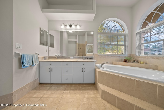 full bath featuring tile patterned flooring, double vanity, a sink, and a bath