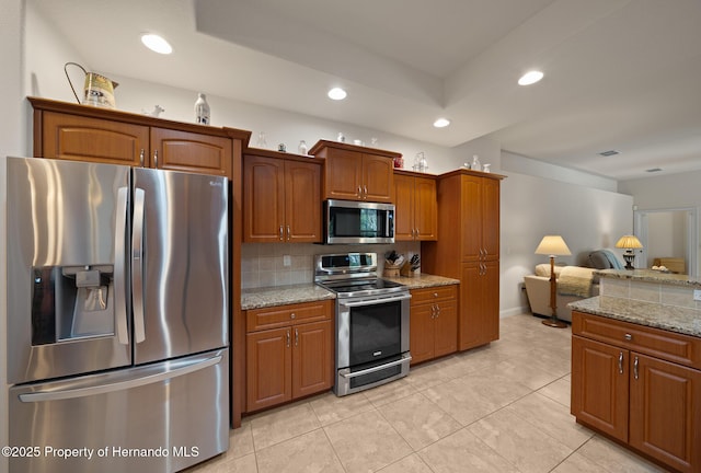 kitchen featuring stainless steel appliances, brown cabinetry, backsplash, and recessed lighting