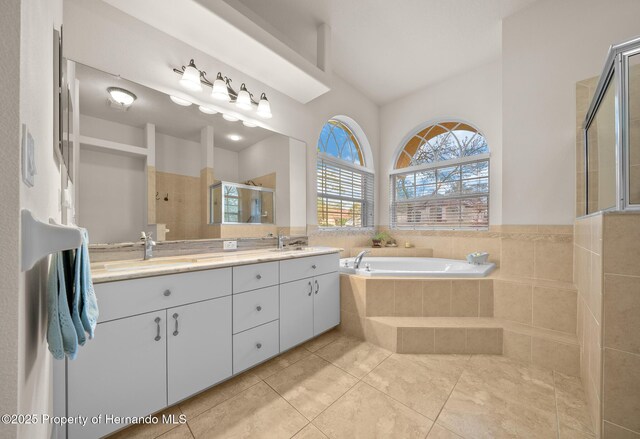 bathroom with double vanity, a stall shower, tile patterned floors, a garden tub, and a sink