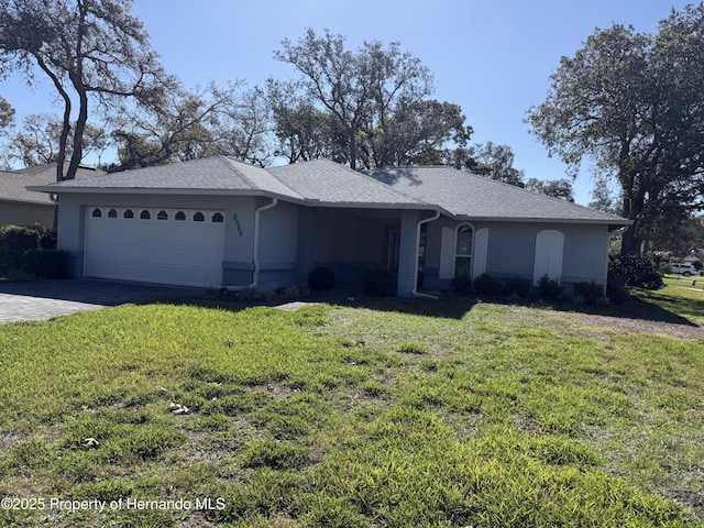 ranch-style home with driveway, stucco siding, an attached garage, and a front yard