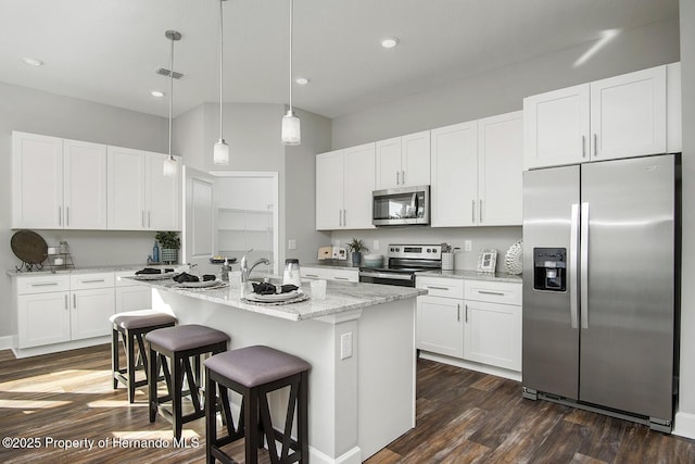 kitchen featuring a center island with sink, a kitchen breakfast bar, dark wood-style flooring, hanging light fixtures, and stainless steel appliances