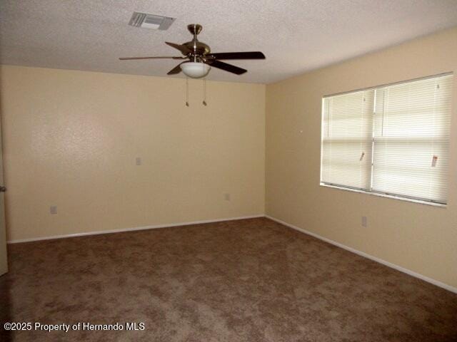 spare room with carpet, visible vents, ceiling fan, and a textured ceiling