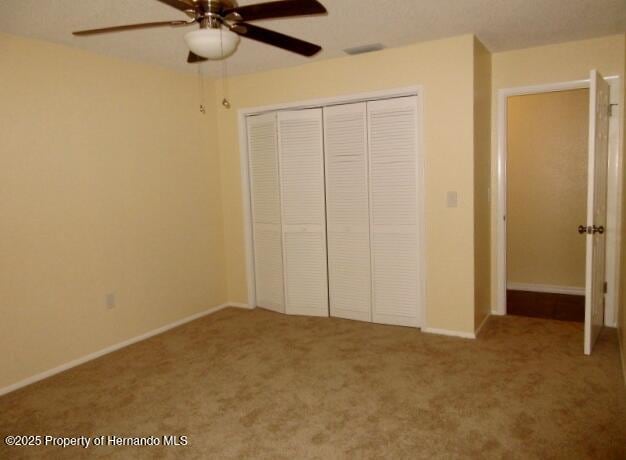 unfurnished bedroom with a ceiling fan, a closet, carpet flooring, and baseboards