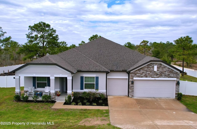 view of front facade with a shingled roof, covered porch, concrete driveway, an attached garage, and fence