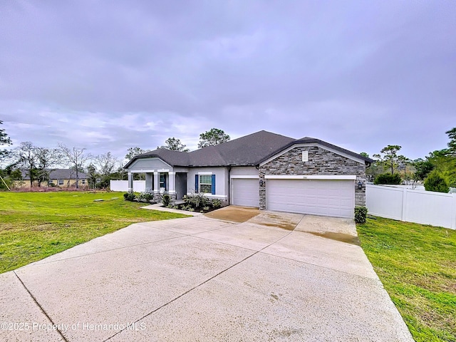 view of front facade featuring a garage, fence, stone siding, driveway, and a front yard