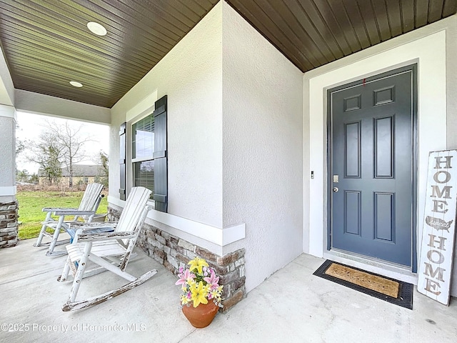 entrance to property with a porch and stucco siding