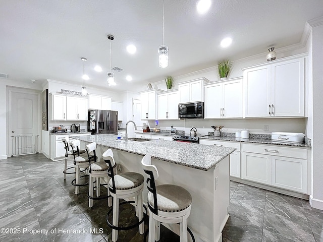 kitchen featuring a center island with sink, stainless steel appliances, a sink, light stone countertops, and a kitchen breakfast bar