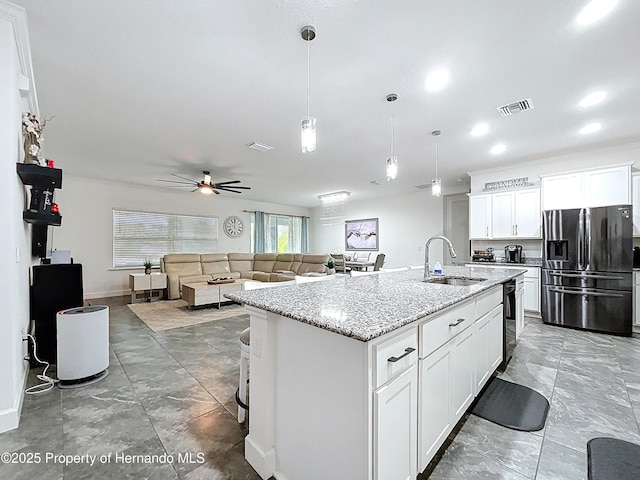 kitchen featuring a sink, a ceiling fan, visible vents, white cabinetry, and stainless steel fridge