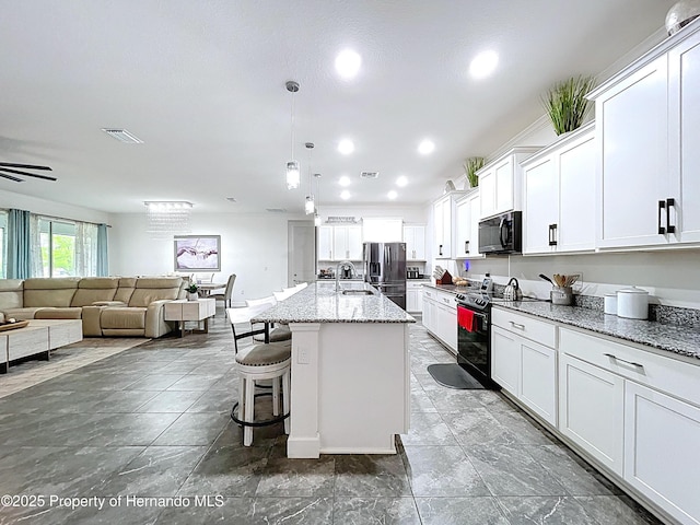 kitchen with electric range, visible vents, open floor plan, black microwave, and stainless steel refrigerator with ice dispenser